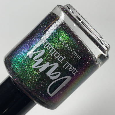 Snake by Dam Nail Polish, black jelly with vivid green multichrome shift and holographic purple reflective glitter, bottle standalone product shot