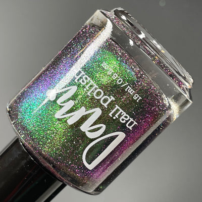 Snake by Dam Nail Polish, black jelly with teal-to-green multichrome and purple reflective glitter, bottle standalone product shot