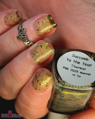 Succumb to the Fear by Danglefoot Nail Polish, black-gold multichrome shimmer flakie thermal bottle held in a light hand