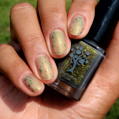 Succumb to the Fear by Danglefoot Nail Polish, black-gold multichrome shimmer flakie thermal bottle held in a light-medium hand