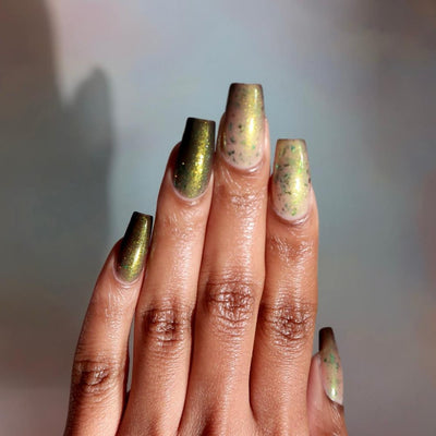 Succumb to the Fear by Danglefoot Nail Polish, black-gold multichrome shimmer flakie thermal on a medium-deep skin tone hand