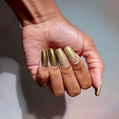 Succumb to the Fear by Danglefoot Nail Polish, black-gold multichrome shimmer flakie thermal on a medium-deep skin tone hand