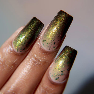Succumb to the Fear by Danglefoot Nail Polish, black-gold multichrome shimmer flakie thermal on a medium skin tone hand