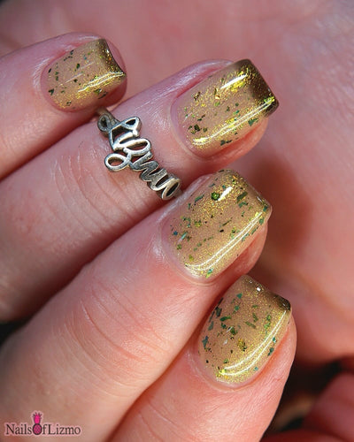 Succumb to the Fear by Danglefoot Nail Polish, black-gold multichrome shimmer flakie thermal on a light skin tone hand