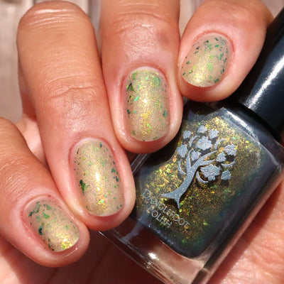 Succumb to the Fear by Danglefoot Nail Polish, black-gold multichrome shimmer flakie thermal bottle held in a light-medium hand