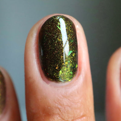 Succumb to the Fear by Danglefoot Nail Polish, black-gold multichrome shimmer flakie thermal on a light-medium skin tone hand