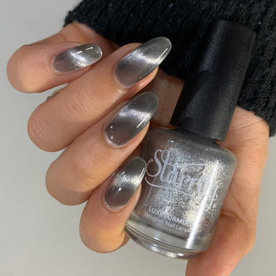 Amulet by Starrily, silver foil magnetic topper with 3D linear cat-eye effect over a smoky grey base, bottle held in a light-medium hand