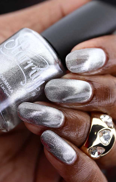 Amulet by Starrily, silver foil magnetic topper with strong 3D cat-eye depth and bold highlight-to-shadow contrast, bottle held in a rich hand