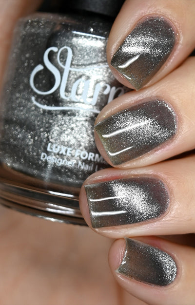 Amulet by Starrily, silver foil magnetic topper with strong linear magnetic pull pattern over a dark olive-grey base, on a light skin tone hand