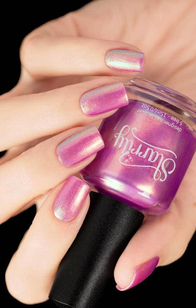 Aphrodite by Starrily, orchid pink shimmer metallic with iridescent lavender and green duochrome shift, bottle held in a light skin tone hand
