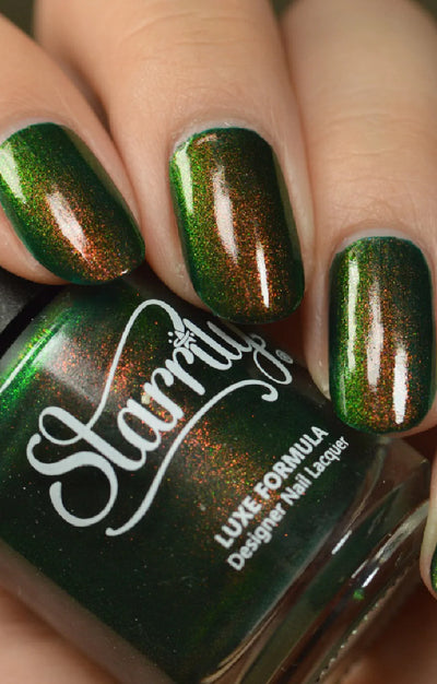 Artemis by Starrily, forest green with warm copper-to-green color-shifting metallic shimmer in studio lighting, bottle held in a light hand