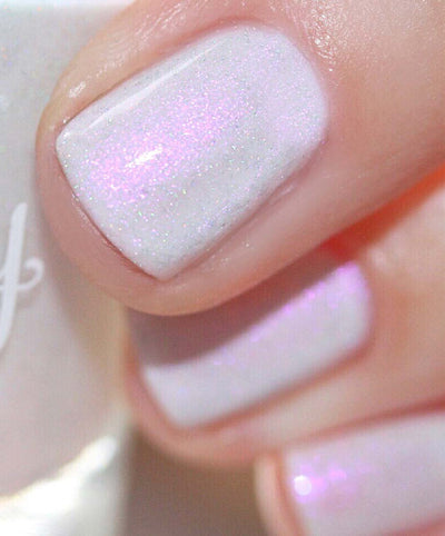 Bean Toes by Starrily, whitish-grey creme with vivid iridescent pink-to-purple shimmer and scattered holographic micro flecks, on a light skin tone hand