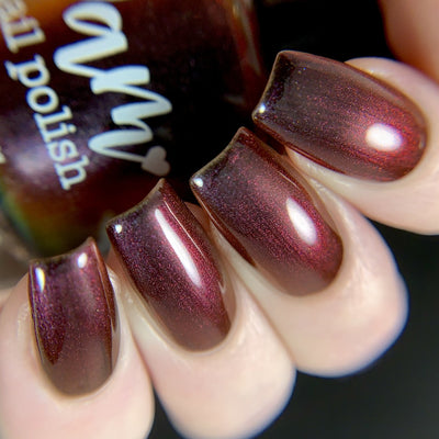 Change of Heart by Dam Nail Polish, deep vampy red multichrome shifting from crimson to warm orange with holographic shimmer, on a light skin tone hand