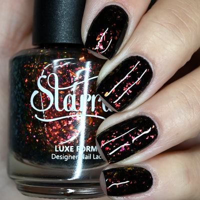 Crunchy Leaves by Starrily, gold-green multichrome flakie topper with burnt orange-to-magenta-pink flake shift over black, bottle held in a light hand