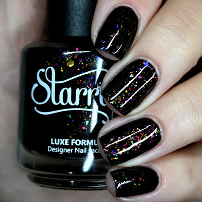 Planet X by Starrily, black flakie jelly with pink, lime green, and blue rainbow color-shifting flakes, bottle held in a light hand