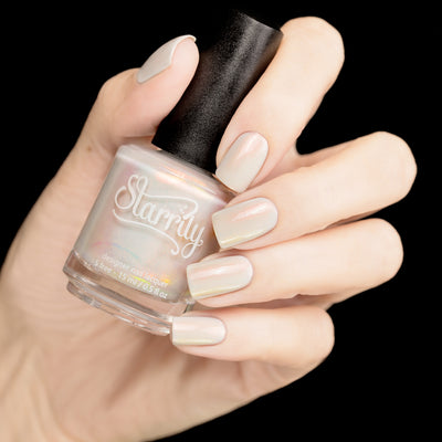 Daisy by Starrily, sheer white-grey base with pearlescent aurora shimmer in muted resting state, bottle held in a light hand