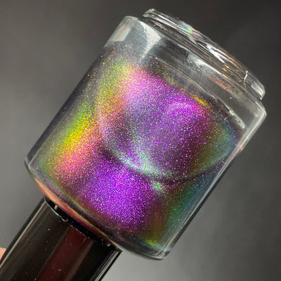 Distant Dimensions by Dam Nail Polish, gold-green multichrome magnetic with holographic microflake shimmer across full shift spectrum, bottle held in hand