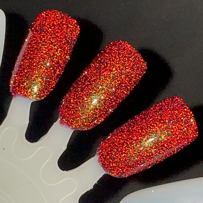 Murder Manor by Dam Nail Polish, intense red and gold reflective micro-glitter over maroon base under direct flash, swatch stick