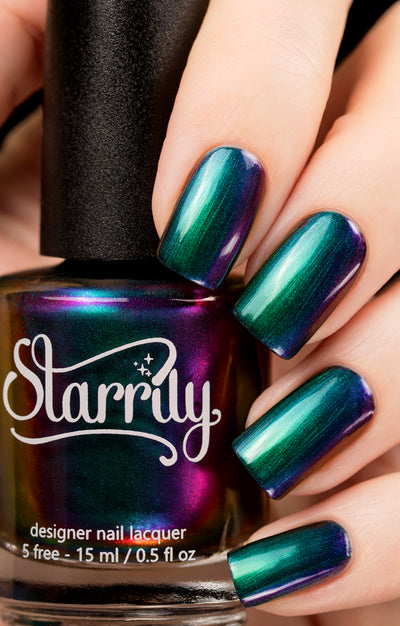 Death Wish by Starrily, purple-green-blue multichrome shifting to teal and violet, bottle held in a light skin tone hand