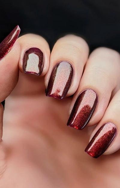 Dragon by Starrily, purple shimmer with copper-rose highlight banding across nails in studio light, on a light skin tone hand