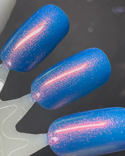 GTFO My Uterus by Dam Nail Polish, royal blue multichrome shimmer with red-orange to gold color shift in studio lighting, swatch stick