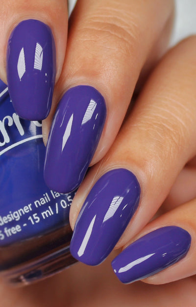 Gravity by Starrily, vivid medium-deep violet-purple creme with strong specular highlights, on a light skin tone hand