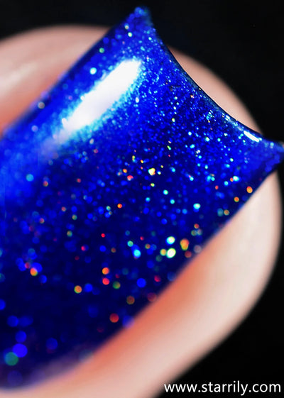 Heart of the Ocean by Starrily, macro close-up of dense sapphire blue holographic micro-flakes scattering orange, red, teal, and green spectral flares under direct flash