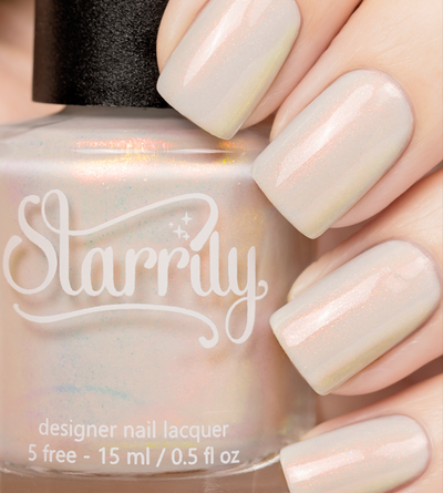 Daisy by Starrily, sheer white-grey shimmer with warm peach-orange iridescent flash, bottle held in a light hand