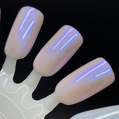 A Whimsical Dream by Dam Nail Polish, sheer warm nude-pink base with vivid blue-violet blurple shimmer flash under direct flash, swatch stick