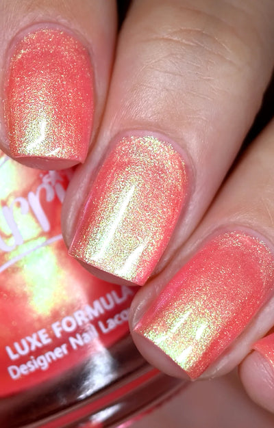 Nectar by Starrily, coral-salmon pink base with strong gold-green multichrome shimmer shift in bright daylight, on a light skin tone hand