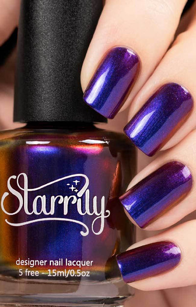 Raven (Multichrome) by Starrily, purple-blue multichrome showing violet-to-royal-blue-to-magenta-red shift, bottle held in a light skin tone hand