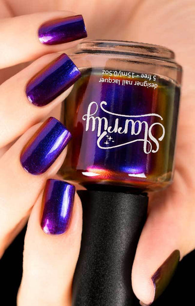 Raven (Multichrome) by Starrily, chrome-like multichrome shifting from violet-purple to royal blue with red visible in bottle, bottle held in a light skin tone hand