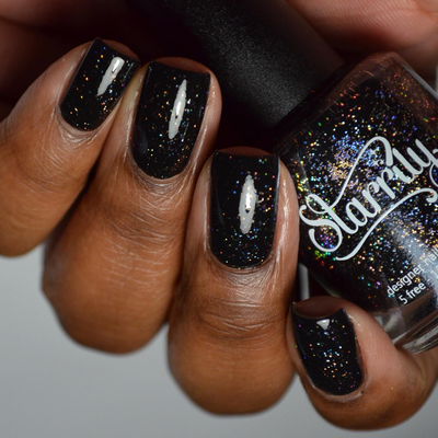 Neutrino by Starrily, jet black holographic glitter with silver and warm gold scatter under studio light, on a deep skin tone hand