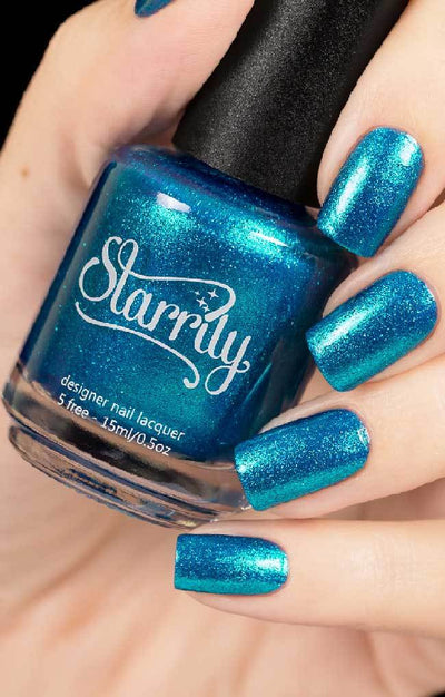 Skyline (Blue Foil) by Starrily, vivid teal-blue micro flakie metallic with high-shine foil luminosity, bottle held in a light hand
