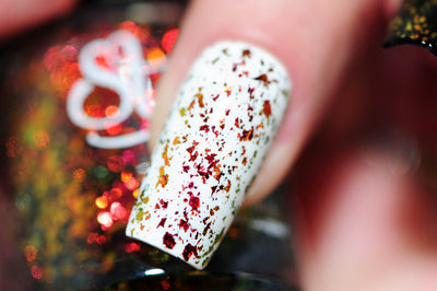 Crunchy Leaves by Starrily, gold-green multichrome flakie topper showing crimson-red to amber-gold to olive-green flake shift over white base, macro close-up of large iridescent flakie shards