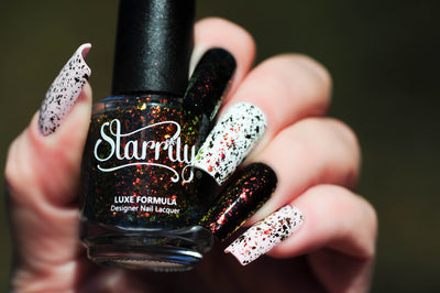 Crunchy Leaves by Starrily, gold-green multichrome flakie topper with orange-to-green shifting flakes over black and white alternating bases, bottle held in a light hand