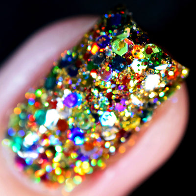 Christmas Lights by Starrily, macro close-up of densely packed red, blue, gold, and rainbow multichrome hex glitters in a clear base on a short natural nail