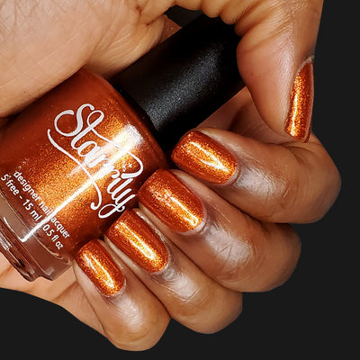 Sunlight (Orange Foil) by Starrily, burnt orange metallic foil with dense micro-flake reflectivity, bottle held in a medium-deep hand