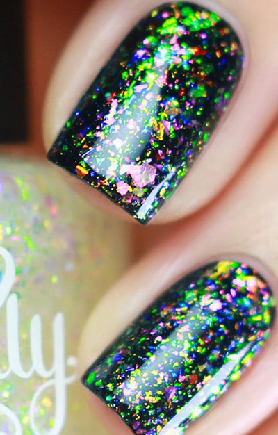Unicorn by Starrily, densely packed rainbow ultrachrome flakies shifting green, pink, blue, and purple over a dark base, on a light skin tone hand