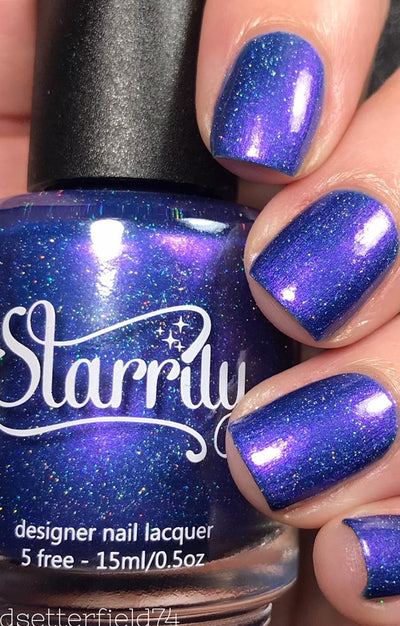 Violet Twilight by Starrily, blue-violet holographic shimmer with scattered rainbow holo flecks and vivid violet shimmer shift under direct flash, bottle held in a light hand