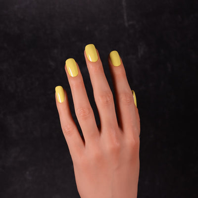 Viscacha by Dimension Nails, glossy creamy yellow creme showing lemon-bright highlight on nails, on a light skin tone hand