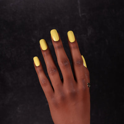 Viscacha by Dimension Nails, bright lemon yellow creme with smoky undertone, on a deep skin tone hand
