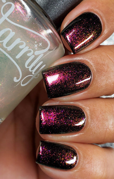 Zephirine by Starrily, pink-orange holographic shimmer topper showing vivid magenta-to-copper iridescence over a near-black base, on a medium skin tone hand