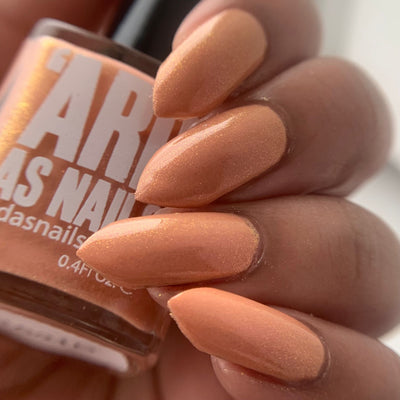Winter Coat by 'Ard As Nails, warm peach-coral holographic shimmer with golden shimmer highlight in bright daylight, on a medium skin tone hand