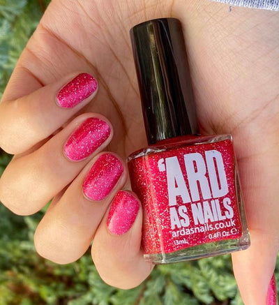 Party Dress by 'Ard As Nails, raspberry red holographic flakie foil with pink-to-red shimmer shift, bottle held in a light skin tone hand