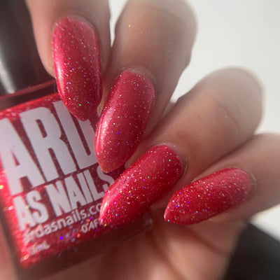 Party Dress by 'Ard As Nails, raspberry red high-shine foil with scattered rainbow holographic flakies, on a light-medium skin tone hand