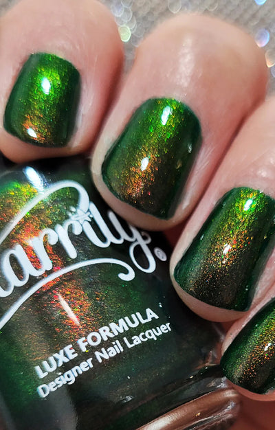 Artemis by Starrily, forest green shimmer reading bright olive-green in direct light and burnt copper in shadow, indoor warm lighting, on a light skin tone hand