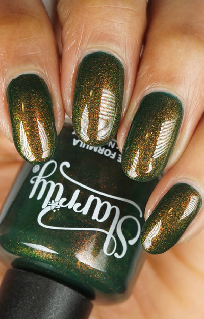 Artemis by Starrily, forest green shimmer emphasizing copper-to-gold-green shift under indoor warm light, bottle held in a light-medium hand