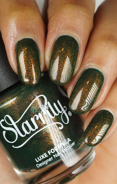 Artemis by Starrily, forest green with fine copper-to-gold-green multichrome shimmer particles, full spectrum visible in studio, bottle held in a light-medium hand