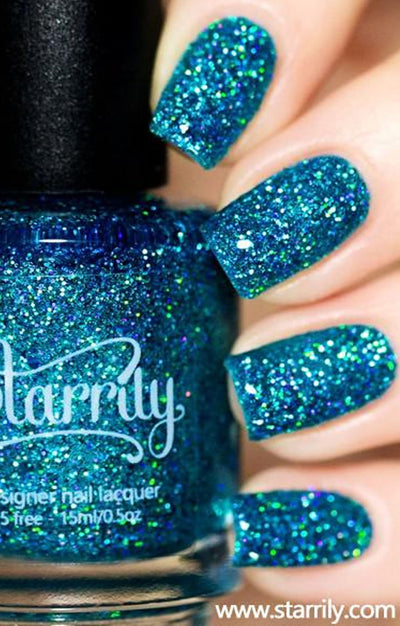 Blitzen by Starrily, teal-blue jelly holographic glitter with green-flash multichrome highlights, bottle held in a light skin tone hand